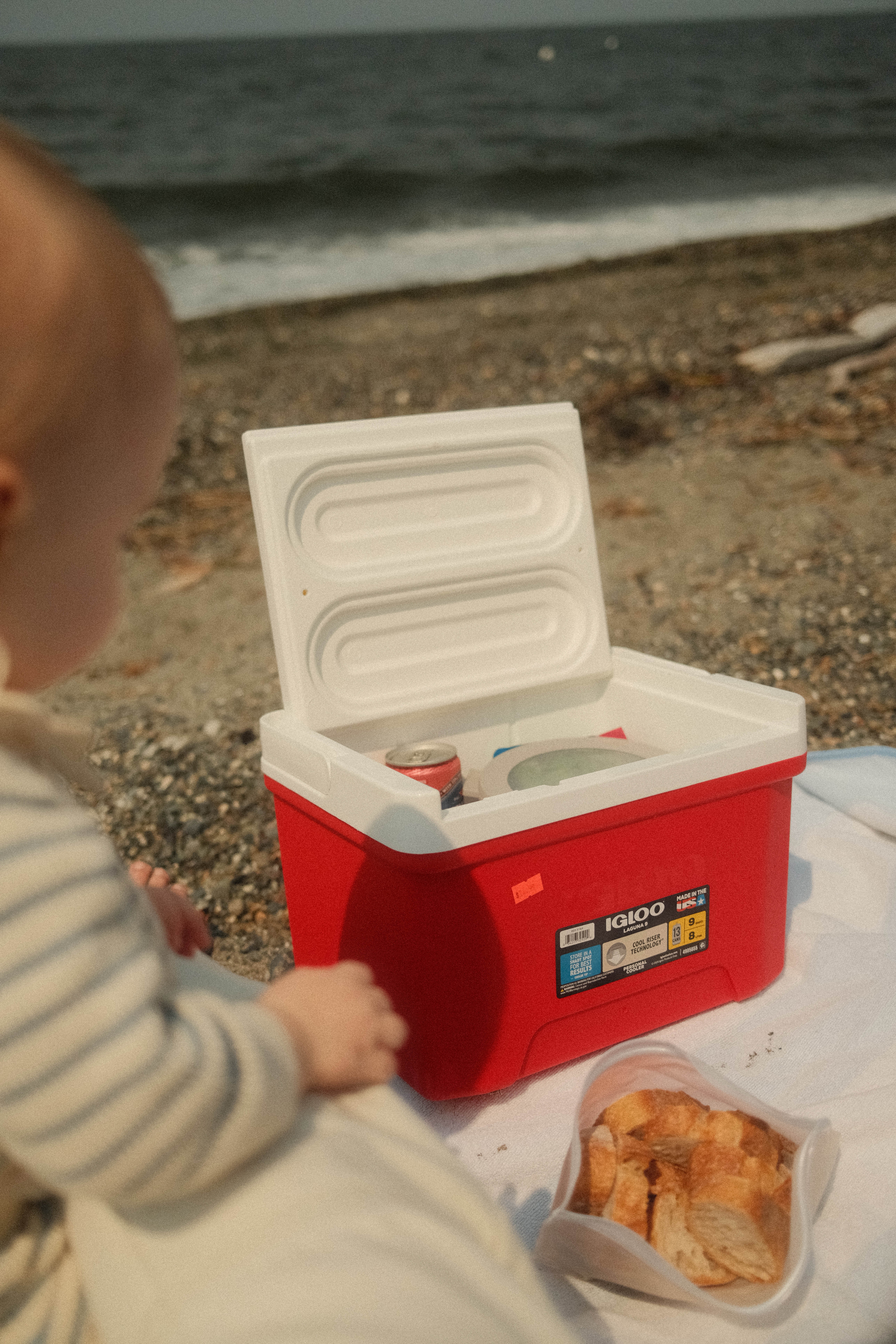 Image of a baby and a picnic cooler on a rocky beach